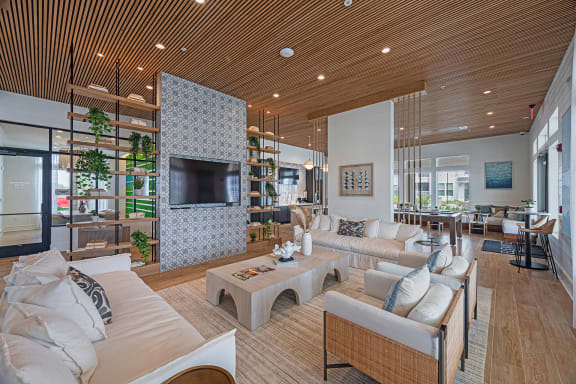 a large living room with white furniture and a large tv on the wall