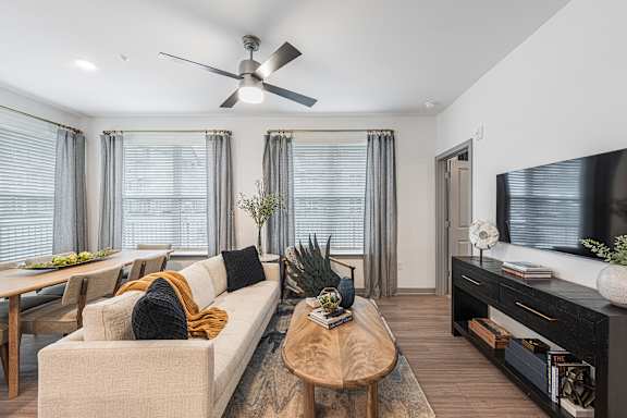 A living room with a beige couch, a wooden coffee table, and a ceiling fan.