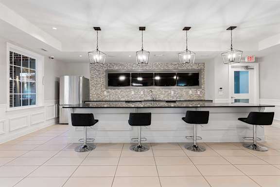 A modern kitchen with a bar area and black stools.