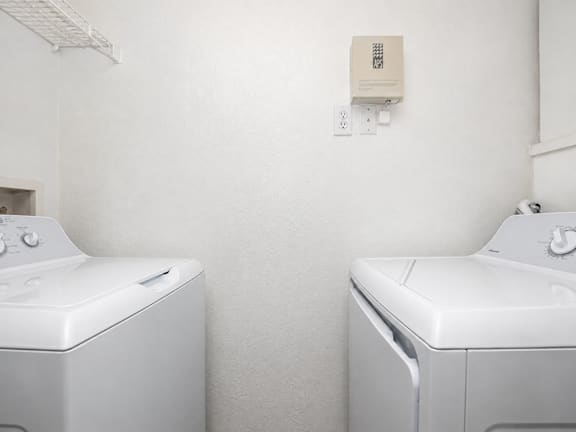 Two white washing machines in a laundry room.