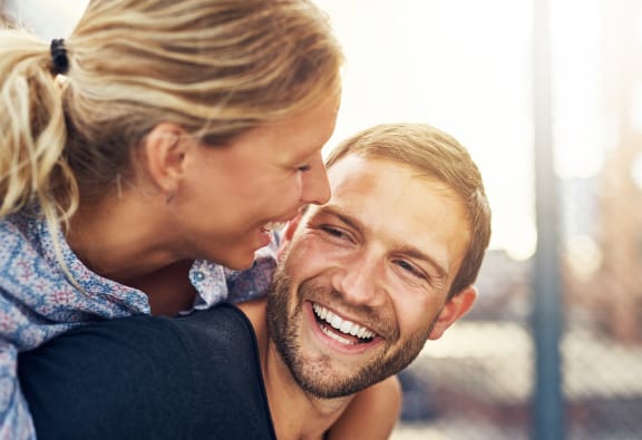 a man with a smile on his face and a woman on his back