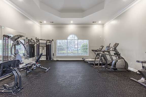 A spacious home gym with a variety of exercise equipment and a large window.