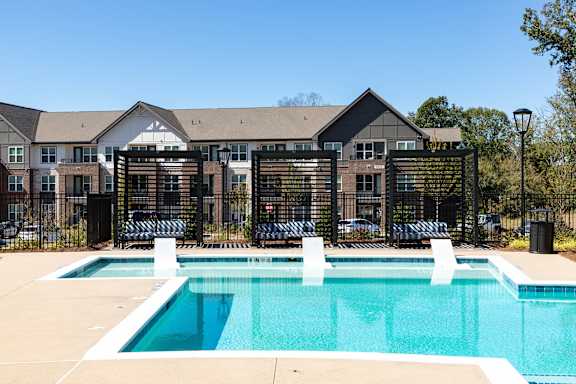 A swimming pool in front of a building with a black fence.