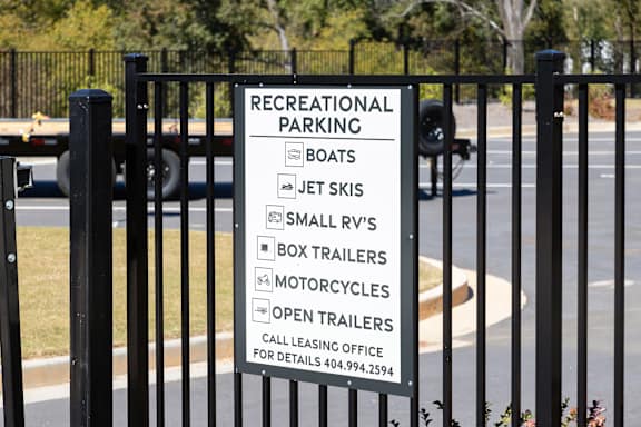 A sign on a gate that says Recreational Parking and lists the types of vehicles allowed.