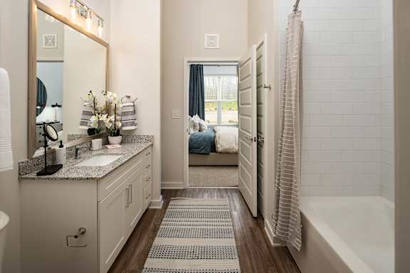 A bathroom with a white tile shower and a white sink.