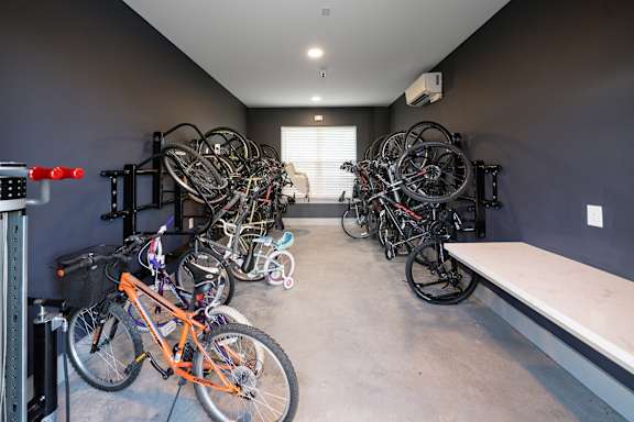 A room with a white bench and a wall-mounted bike rack holding several bicycles.