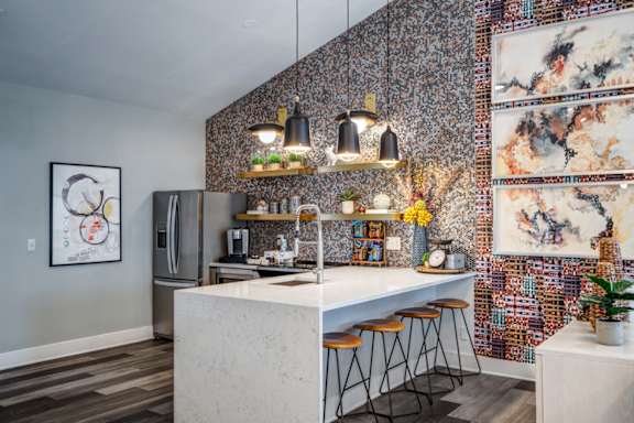 A kitchen with a white counter and a wall covered in a mosaic of different paintings.