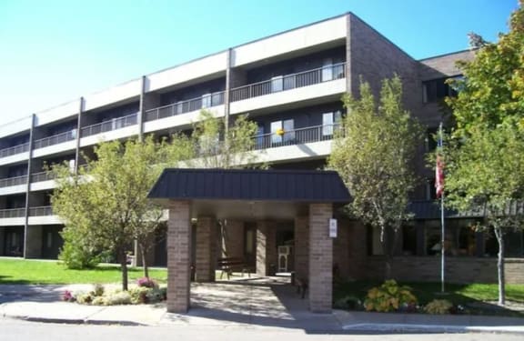 a building with a black roof and trees in front of it