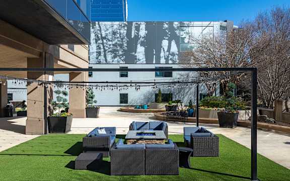 A modern outdoor seating area with a large screen displaying an image of a tree.