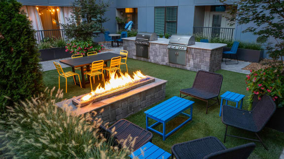 a fire pit in the middle of a yard with chairs and tables
