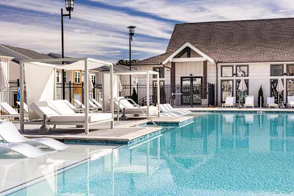 A pool with sun loungers and a building in the background.
