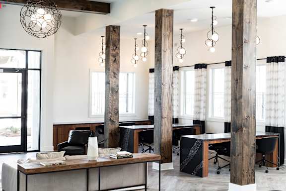 A modern office space with wooden pillars and black chairs.