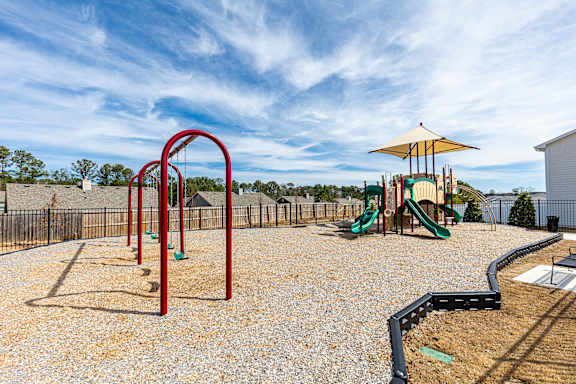 A playground with a red swing set and a green slide.