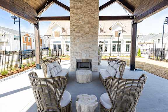 A patio with a fireplace and chairs.
