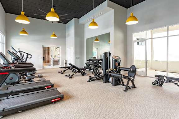 A spacious gym with treadmills, exercise bikes, and weights.