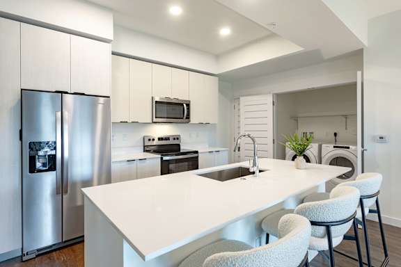 A modern kitchen with a white island and stainless steel appliances.
