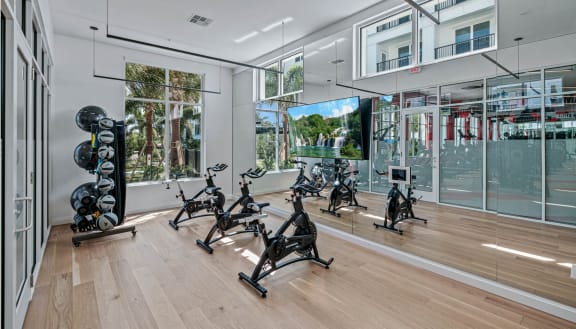 the home gym has a wall of windows and a wood floor at Altis Grand Lake Willis, Orlando, FL
