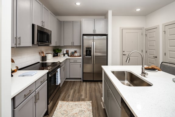 a large kitchen with white counter tops and stainless steel appliances