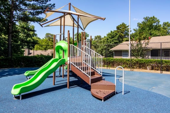 a playground with a green slide and a brown wooden platform