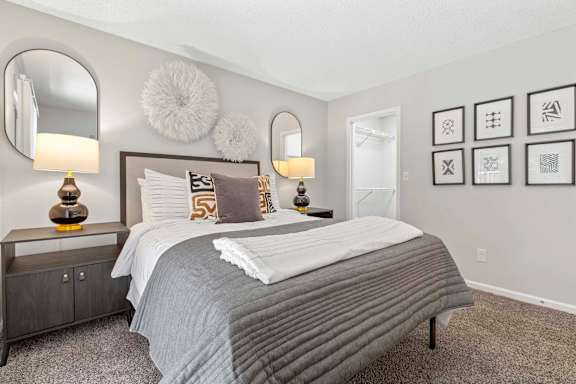 A bedroom with a large bed and two lamps.
