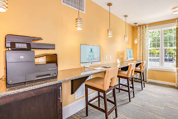A room with a desk, chairs, and a printer.