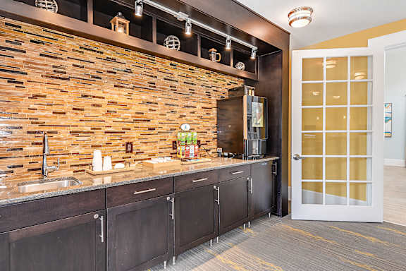 A kitchen with a stone wall and wooden cabinets.