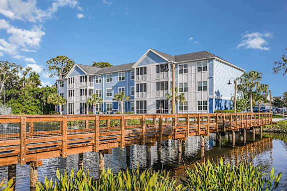 A wooden bridge over a body of water with a building in the background.