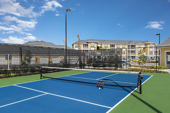 A tennis court with a blue surface and a green border.