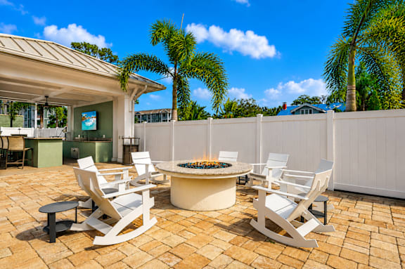 A patio with a fire pit and chairs.