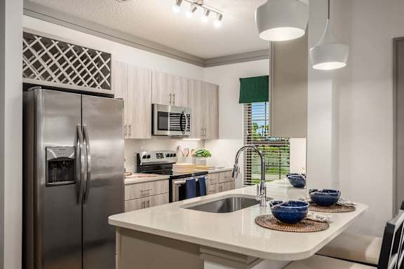 A modern kitchen with a stainless steel refrigerator and a white countertop.