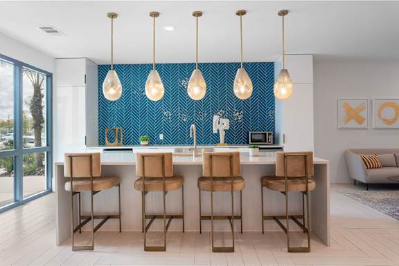 A kitchen with a blue backsplash and wooden bar stools.