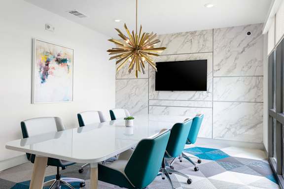 A conference room with a white table and blue chairs.