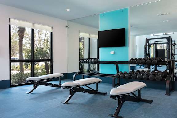 A gym with a row of benches and a television.