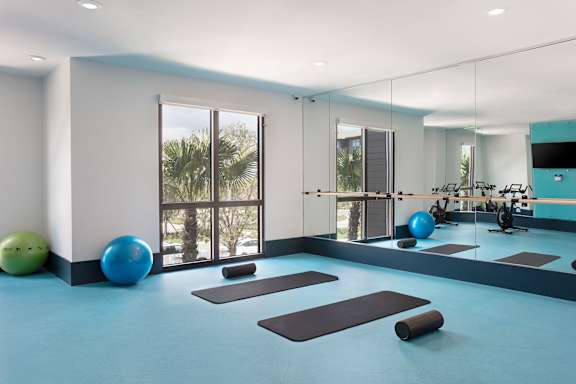 A gym with exercise equipment and a mirror on the wall.