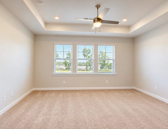 A room with a ceiling fan and carpeted floor.