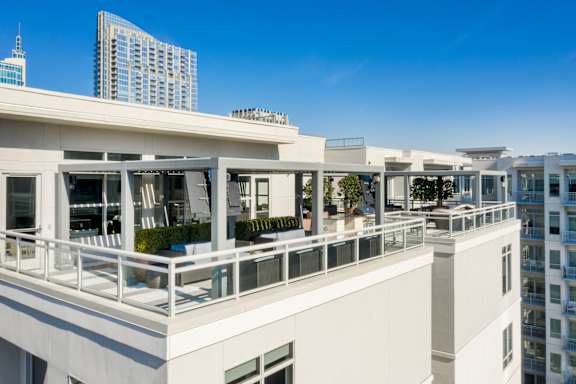 A white building with balconies overlooks a cityscape.