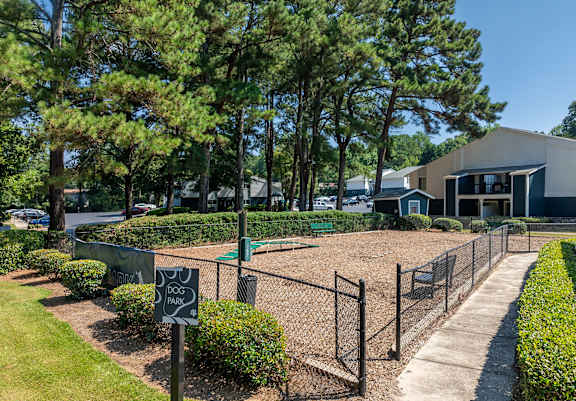 A dog park sign is displayed in front of a fenced area.