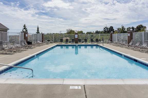 A large outdoor swimming pool surrounded by a metal fence.