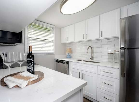 A kitchen with white cabinets and a marble countertop.