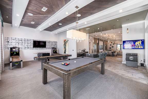 A room with a pool table and a TV mounted on the wall.