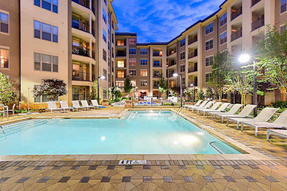 A large swimming pool surrounded by lounge chairs and trees.