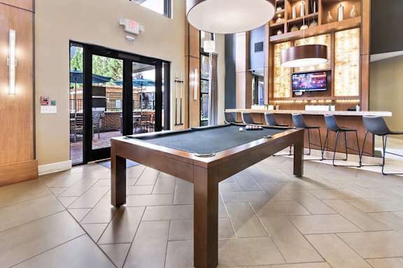 A pool table in a room with a television and a bar.
