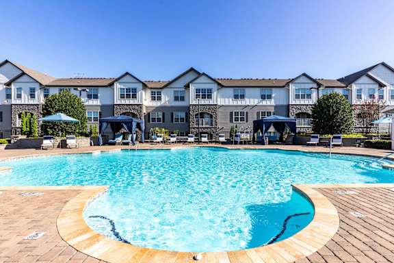 A large swimming pool in front of a building with a clear blue sky above.