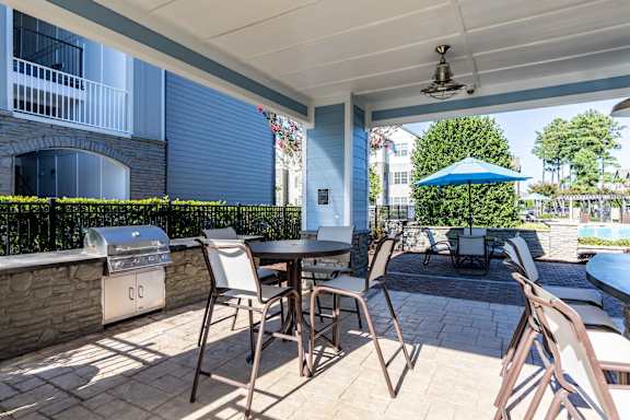 A patio with a table and chairs and a grill.