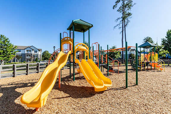 A playground with a yellow slide and a green roofed structure.