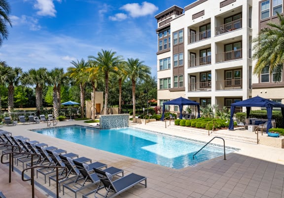 a swimming pool with lounge chairs in front of a building