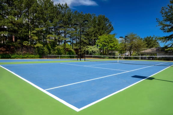 a tennis court with trees in the background at Crestmont at Thornblade, Greenville
