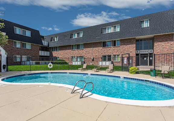 A swimming pool in front of a brick building.