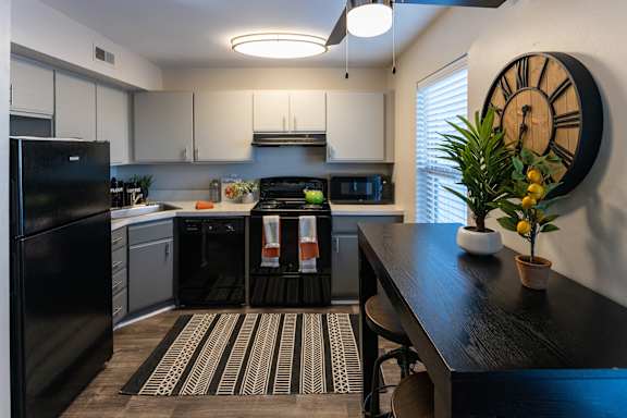 a kitchen with white cabinets and a black and white rug