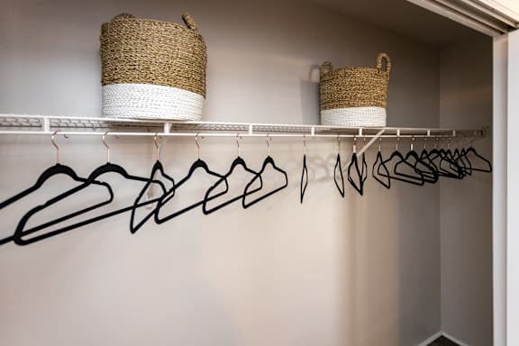 a closet with a coat rack and hooks and a pair of baskets on the wall